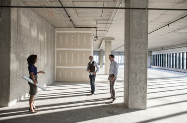 Ein gemischtes Team von Geschäftsleuten besichtigt ein neues, leerstehendes Bürogebäude. - MINF08545