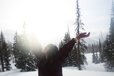 Eine schöne Frau lächelt beim Wandern durch ein unberührtes Schneefeld bei Sonnenuntergang in Wyoming. - AURF00149