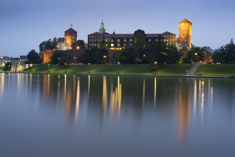 Polen, Krakau, Blick auf das Schloss Wawel mit der Weichsel im Vordergrund in der Abenddämmerung, lizenzfreies Stockfoto