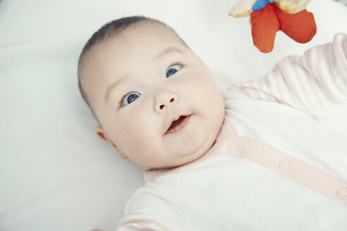 Lächelndes Baby auf dem Bett liegend, Porträt - AZF00088