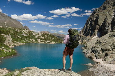 A woman hiker rests next to turquoise lake, Weminuche Wilderness, Colorado. - AURF00164