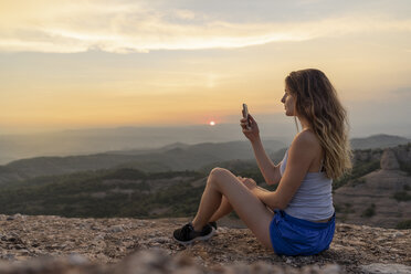 Spain, Catalonia, Sant Llorenc del Munt i l'Obac, woman taking pictures in the mountains with her smartphone - AFVF01386