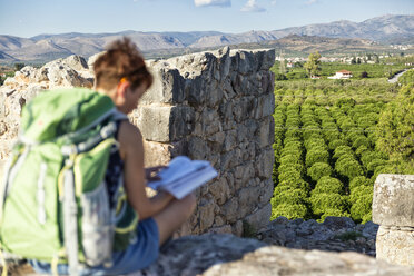 Griechenland, Peloponnes, Argolis, Tiryns, archäologische Stätte, Touristin liest Reiseführer - MAMF00195