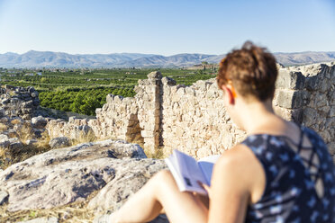 Griechenland, Peloponnes, Argolis, Tiryns, archäologische Stätte, Touristin liest Reiseführer - MAMF00198