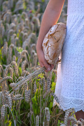 Mädchen steht in einem Weizenfeld und hält frisches Brot - LBF02019