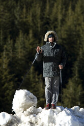 Ein Mann auf einer Schneewehe nach einem Skitag mit Kiefern im Hintergrund. - AURF00190