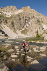 A man jumping across rocks over a lake in the Weminuche Wilderness, San Juan National Forest, Colorado. - AURF00211