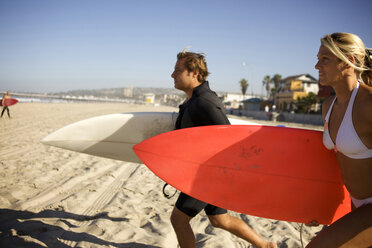 Ein Mann und eine Frau rennen an einem frühen Morgen in Pacific Beach, San Diego, Kalifornien, zum Wasser, um das erste Mal an diesem Tag zu surfen. - AURF00221