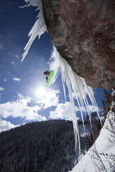 Ein männlicher Snowboarder springt an einem sonnigen Tag in Colorado von einer Eiswasserfallklippe. - AURF00236
