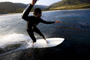 Ein männlicher Surfer macht eine Drehung beim Reiten einer Welle im Leo Carrillo State Park in Malibu, Kalifornien. - AURF00253