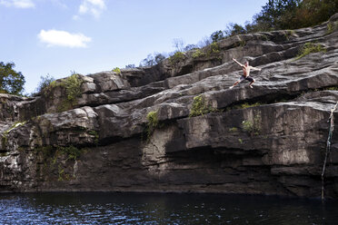 Junger Mann springt von Felsklippen in eine Lagune im High Falls Park, Geraldine, Alabama. - AURF00261