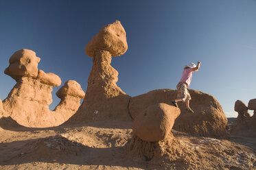 Junges Mädchen springt von Felsen im Goblin Valley State Park, Hanksville, Utah. - AURF00264