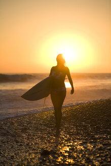 Junge Frau geht nach dem Surfen am Strand spazieren, Mexiko. - AURF00299