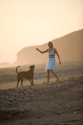 Young woman playing with her dog on beach in Mexico. - AURF00303