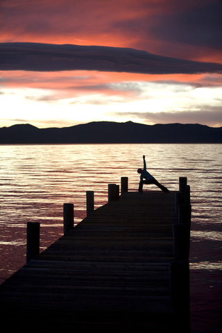 Junge Frau beim Yoga auf dem Pier in Tahoe City, CA., lizenzfreies Stockfoto