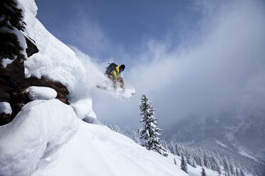 Ein Snowboarder springt von einer Klippe in den Pulverschnee in Colorado. - AURF00343
