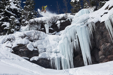 Ein Snowboarder springt in Colorado von einer Eiswasserfallklippe in den Pulverschnee. - AURF00353