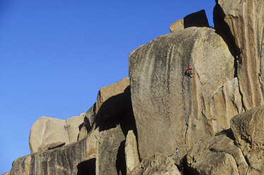Ein Felskletterer und sein Sichernder wirken klein gegen die große Felswand. - AURF00356