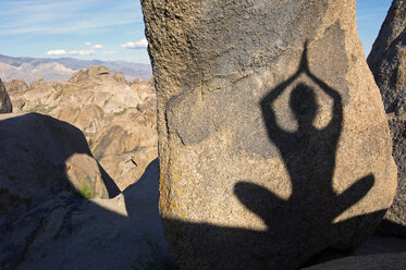 Der Schatten einer Frau, die Yoga praktiziert, auf einem Felsen. - AURF00357