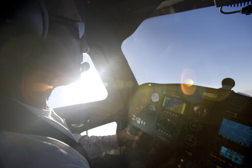 Eine sonnenbeschienene Ansicht eines Piloten, der sein Flugzeug fliegt und in den blauen Himmel schaut. - AURF00390