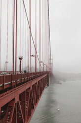 A small sailboat passes under the Golden Gate Bridge on a foggy day in San Francisco, California. - AURF00391