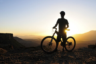 Die Silhouette eines Mountainbikers bei Sonnenuntergang auf Gooseberry Mesa im Süden Utahs. - AURF00393