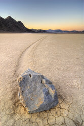 A rock leaves a trail of its movement across the The Racetrack in Death Valley National Park at sunset, CA. - AURF00400