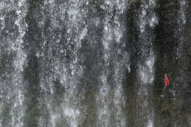 Eine Frau läuft hinter einem Wasserfall im Silver Falls State Park, Oregon, USA. - AURF00411