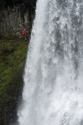Eine Frau läuft hinter einem Wasserfall im Silver Falls State Park, Oregon, USA. - AURF00412