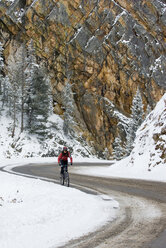 Eine Frau fährt im Winter mit ihrem Fahrrad den Red Mountain Pass hinauf, Ouray, Colorado. - AURF00416