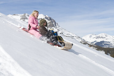 A young girl and boy sledding down hill in the San Juan National Forest, Colorado. - AURF00420