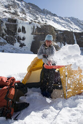 Eine Frau schaufelt beim Wintercamping in den Sangre De Cristo Mountains, Colorado, den Schnee von ihrem Zelt weg. - AURF00423