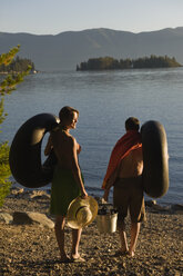 A young couple prepare to float on the lake in inner tubes during a hot summer day. - AURF00431