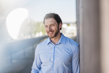 Portrait of smiling businessman at concrete wall - DIGF04815