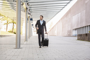 Businessman on the move pushing rolling suitcase - DIGF04828