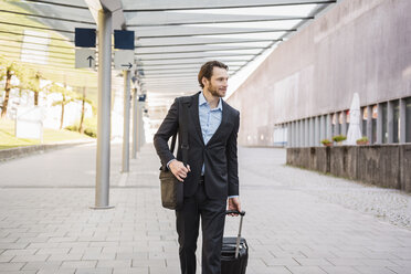 Businessman on the move pushing rolling suitcase - DIGF04829