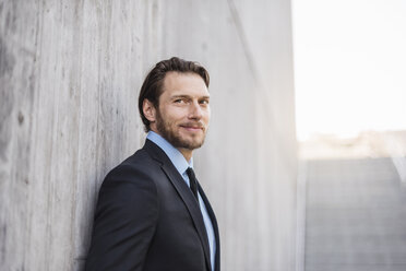 Portrait of confident businessman at concrete wall - DIGF04837