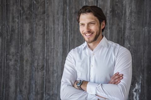 Porträt eines lächelnden Geschäftsmannes an einer Betonwand, lizenzfreies Stockfoto