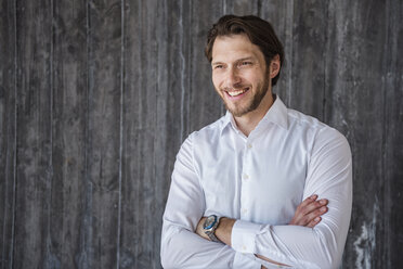 Portrait of smiling businessman at concrete wall - DIGF04851