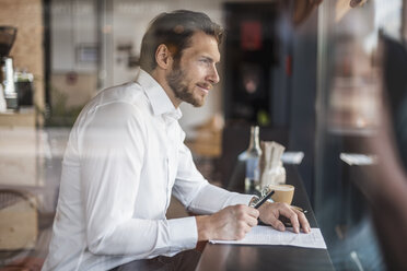 Businessman in a cafe taking notes - DIGF04858