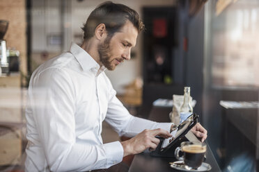 Businessman using tablet in a cafe - DIGF04859