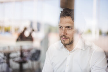 Portrait of businessman looking out of window - DIGF04862