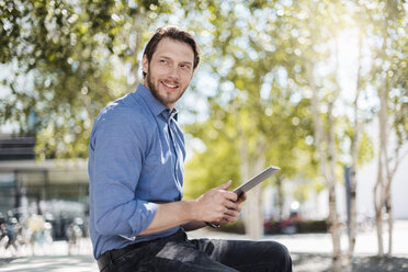 Smiling businessman using tablet outdoors in the nature - DIGF04870