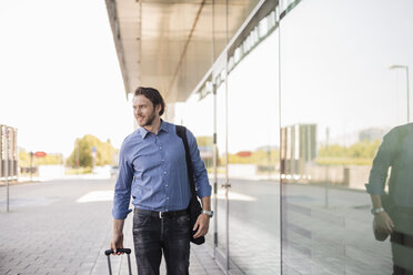 Businessman with rolling suitcase and laptop bag outoors - DIGF04875