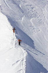 Zwei Männer wandern mit Skiern den Weg hinauf, um abseits der Pisten in St. Anton am Arlberg, Österreich, unverspurten Schnee zu fahren. - AURF00486