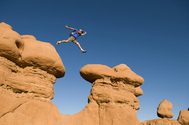 Man jumping between rock spires, Goblin Valley State Park, Hanksville, Utah. - AURF00530