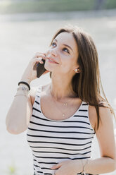 Lächelnde junge Frau mit Smartphone an der Uferpromenade - GIOF04136