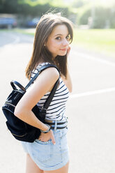 Portrait of smiling young woman with backpack outdoors in summer - GIOF04145