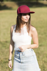 Young woman wearing baseball cap standing on a meadow - GIOF04170