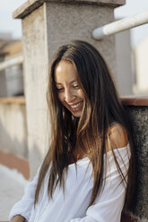 Porträt einer lachenden jungen Frau, die sich auf einer Dachterrasse entspannt - AFVF01404